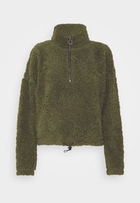 Sudadera de forro polar verde oliva con cuello alto, medio cierre frontal y dobladillo con cordón ajustable. Superficie texturada y suave con un aspecto acogedor.