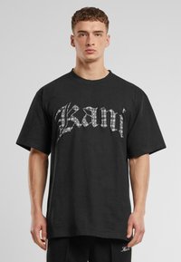 Black cotton t-shirt with a loose fit, featuring a prominent white graphic design of the word "Kanji" across the front.