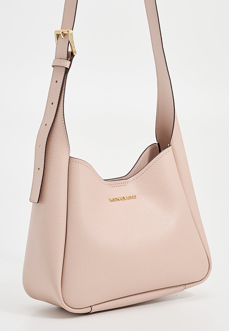 Sac à épaule en cuir rose clair avec bandoulière ajustable et logo doré "Michael Kors" à l'avant.