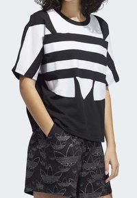 Svart och vit kortärmad t-shirt med djärva horisontella ränder och en stor grafisk design på framsidan. Tillverkad av bomull.