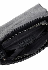 Interno di una borsa a mano in pelle nera con chiusura a zip. Presenta una texture liscia, una fodera in tessuto e un'etichetta tessuta all'interno.