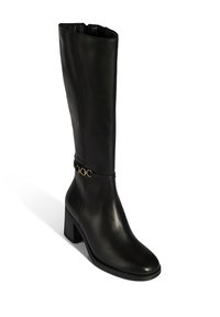 Botte noire en cuir montant jusqu'au genou avec un talon bloc, décorée d'une chaîne dorée autour de la cheville et une finition lisse et polie.