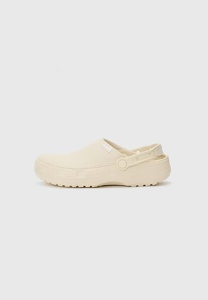 Sabot crème à enfiler avec une semelle en caoutchouc texturé, sangle unique pour un ajustement réglable, matière supérieure lisse et détails de marque minimalistes.
