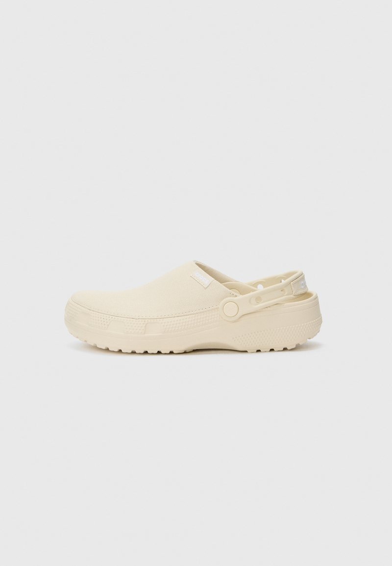 Sabot crème à enfiler avec une semelle en caoutchouc texturé, sangle unique pour un ajustement réglable, matière supérieure lisse et détails de marque minimalistes.