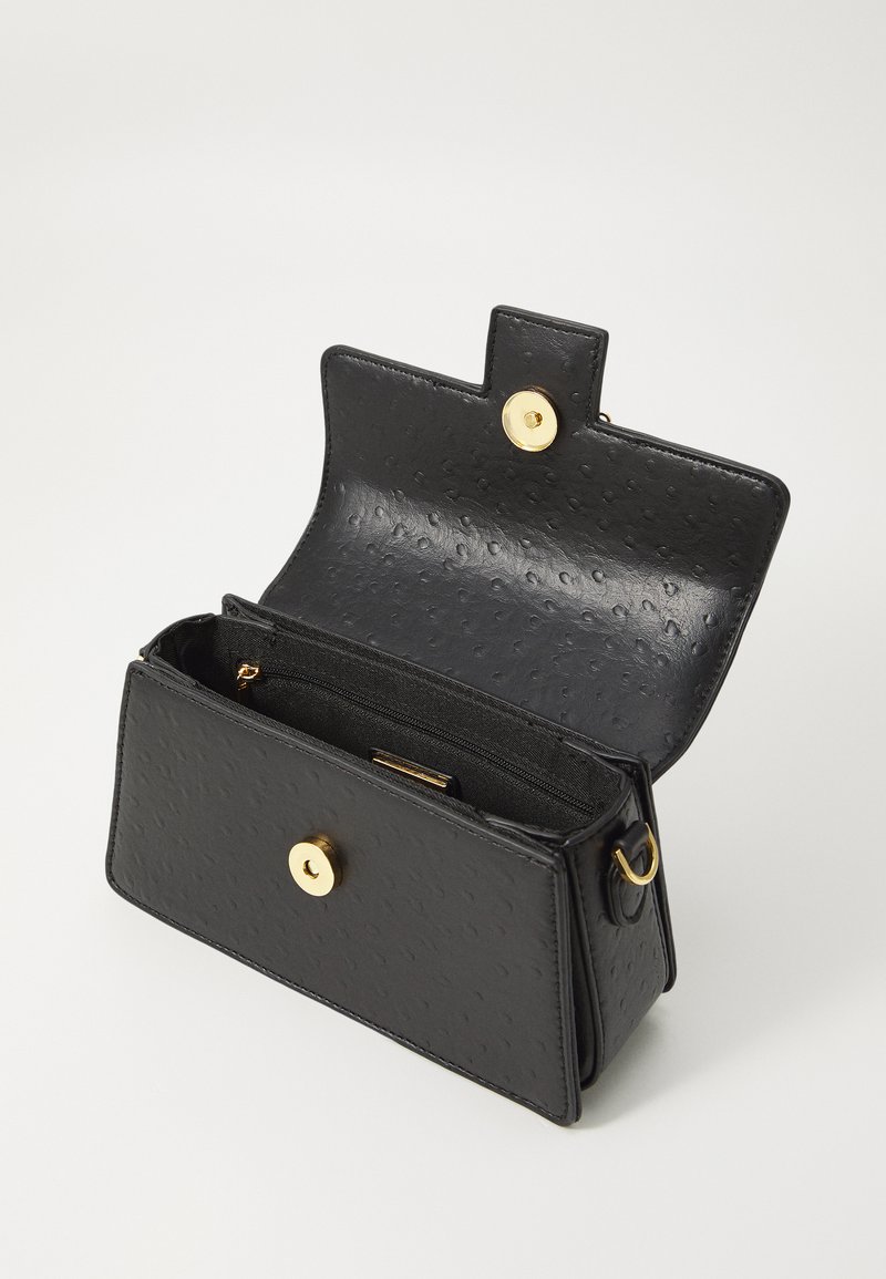 Sac à main en faux cuir noir avec une surface texturée, fermeture à pression dorée et poche zippée intérieure. Design rectangulaire compact.