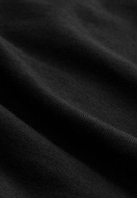 Schwarzer Stoff mit weicher Textur, feiner Rippenstruktur und sanften Falten, die seine glatte und gleichmäßige Oberfläche betonen.