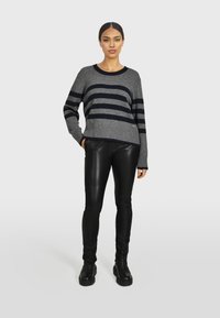 Maglione a righe grigio e blu navy con scollatura rotonda e orlo a coste, abbinato a pantaloni in pelle nera e stivali neri robusti.