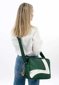 Grøn skuldertaske med sølv- og hvide detaljer, rektangulært design, stoftekstur, justerbar rem og en rund nøglering fastgjort.