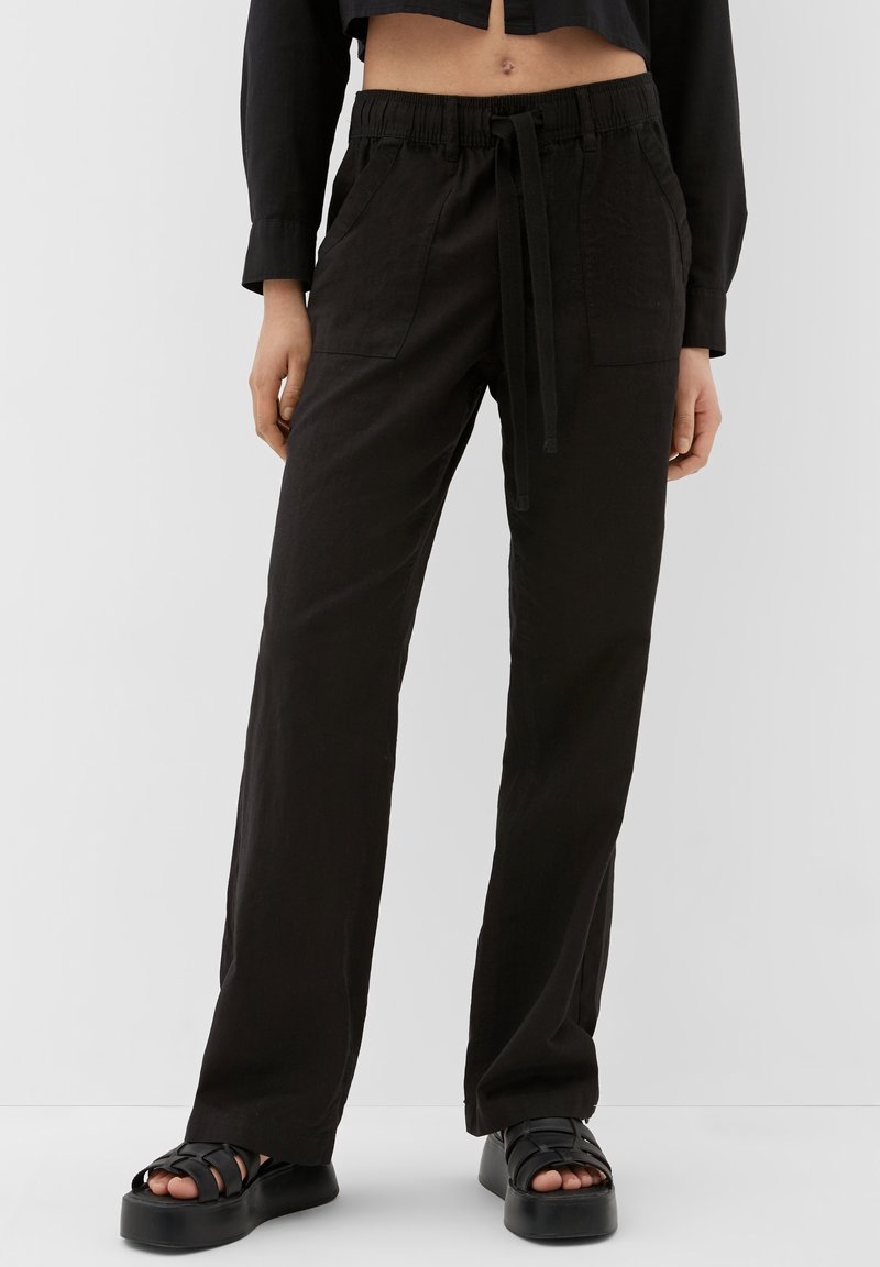 Pantalon noir ample avec une taille élastique et un cordon de serrage ajustable. Comprend deux poches avant et une texture lisse.