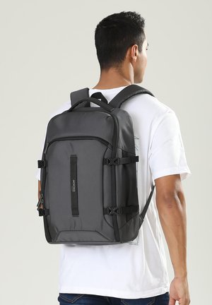 Zaino grigio con più scomparti, spallacci regolabili e dettagli con fibbia. Realizzato in materiale resistente, con un design elegante e strutturato.