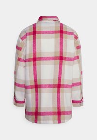 Camicia di flanella a quadretti in bianco, beige e tonalità di rosa. Presenta un colletto e maniche arrotolate, con un taglio largo e informale.