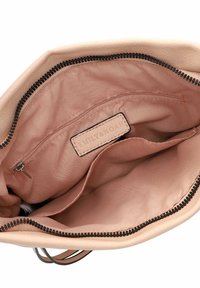 Intérieur d'un sac à main en cuir beige avec une poche zippée, doublure en satin et une étiquette. Comprend une fermeture éclair supérieure avec quincaillerie noire.