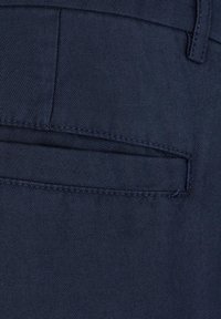 Pantaloni blu navy realizzati in un tessuto liscio e testurizzato. Presentano una tasca posteriore con cucitura nascosta. Linee pulite e design su misura.