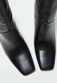 Stivaletti neri in pelle, con una forma della punta quadrata, caratterizzati da una superficie liscia e un design minimalista senza hardware o dettagli visibili.