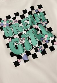 Tela de algodón con un estampado multicolor que incluye la frase "DREAM GIRL" en verde, rodeada de flores, caras sonrientes y corazones sobre un fondo a cuadros.