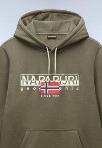 Sudadera color verde oliva hecha de algodón con un bolsillo frontal. Presenta un logo blanco, texto gráfico y un acento de la bandera noruega.