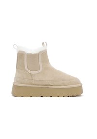Stivaletti in suede beige con una morbida fodera in pelliccia bianca, pannelli laterali in elastico e una robusta suola in gomma beige. Due linguette posteriori.