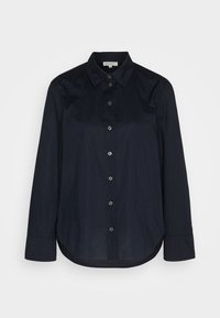 Chemise noire à manches longues boutonnée, col pointu et ourlet arrondi, posée à plat montrant le devant et sept boutons visibles.