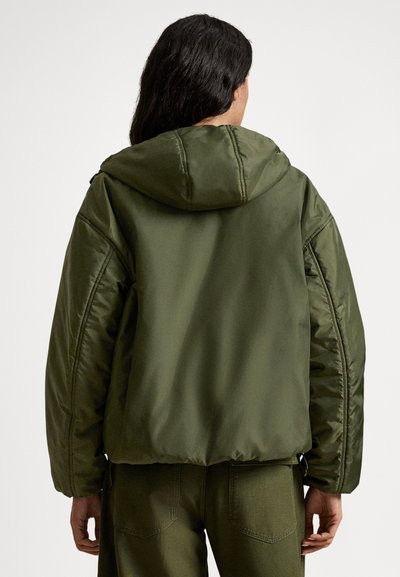 Χακί πράσινο bomber μπουφάν με κουκούλα, επενδυμένη υφή και ριμπ μανσέτες. Διαθέτει άνετη εφαρμογή και εμφανείς ραφές στα μανίκια.