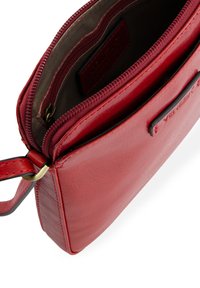 Red leather wristlet with zipper closure, visible interior pocket, and stitched brand label on front.