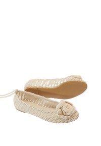 Bailarinas de ganchillo en color beige con un acento floral en la punta. El diseño de malla abierta y la suela de goma plana ofrecen transpirabilidad y comodidad.