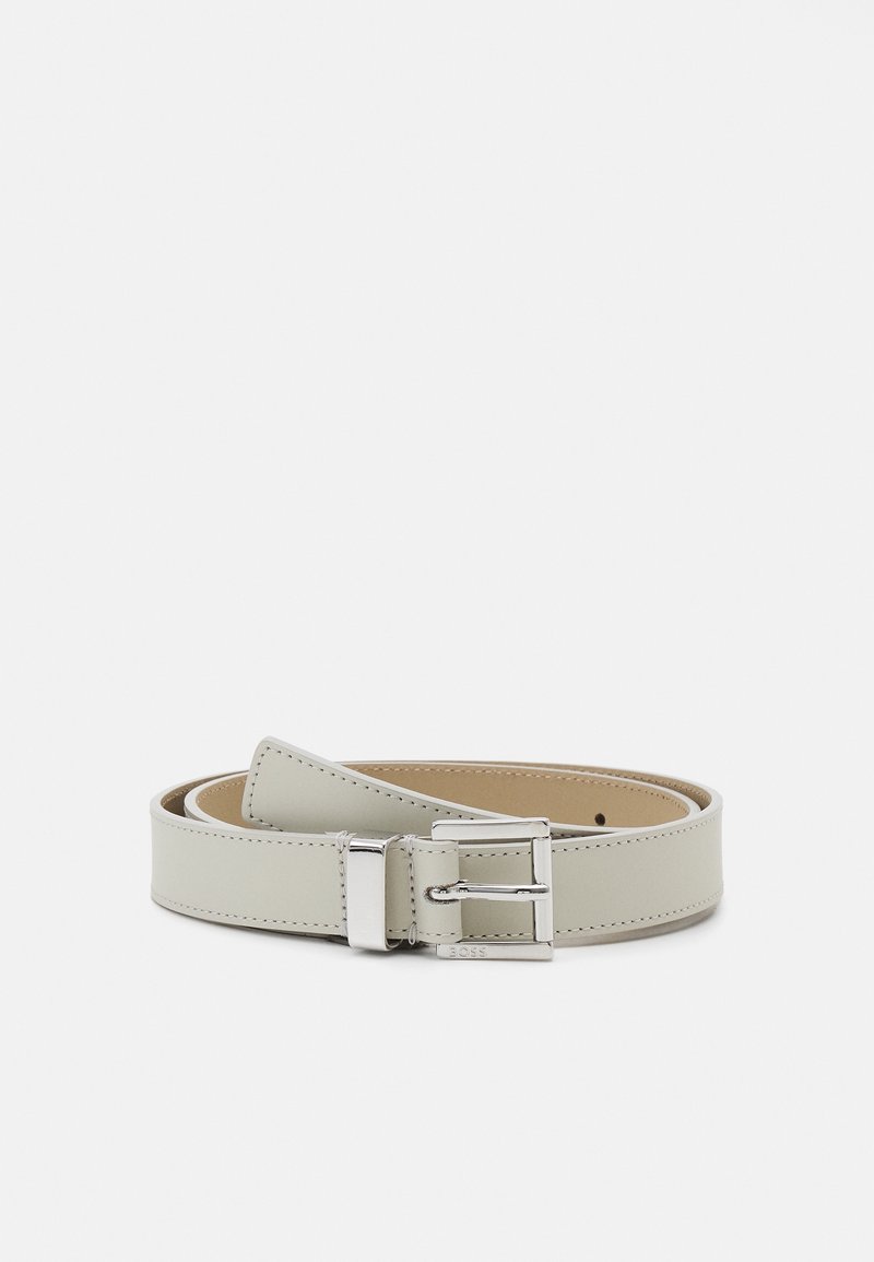 Ceinture en cuir gris clair avec boucle rectangulaire argentée et bords cousus, enroulée sur un fond blanc.