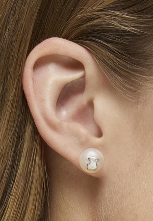 Orecchino a perla con un design di animale in argento al centro, texture liscia, forma rotonda e colore bianco con finitura lucida.
