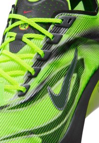 Limoengroene Nike hardloopschoen met een gestructureerd bovenwerk, zwarte accenten, contrasterende veters en een kenmerkend Swoosh-ontwerp.