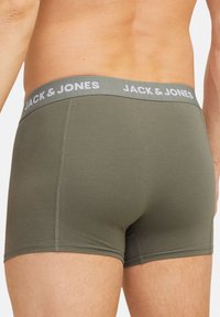 Olivgrüne Boxershorts mit einem grauen elastischen Bund, der das Logo "JACK & JONES" trägt. Glatte Stofftextur und enganliegendes Design.