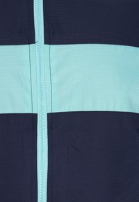 Jachetă cu fermoar de culoare bleumarin și albastru deschis, cu un model texturat. Prezintă dungi orizontale contrastante și un fermoar neted.