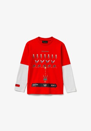 T-shirt rouge à manches longues avec des manches blanches, un imprimé graphique de squelettes et de papillons, un texte logo, et une bande ourlet texturée en bas.