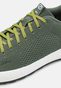 Zielone siateczkowe sneakersy z żółtymi i czarnymi wzorzystymi sznurówkami, białą podeszwą środkową oraz teksturowaną cholewką z detalem logo na języku.