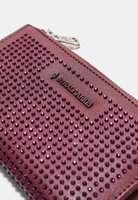 Fialová peňaženka z ekokože s strieborným zipsom, embosovaným logom a povrchom ozdobeným malými, lesklými fialovými kamienkami.