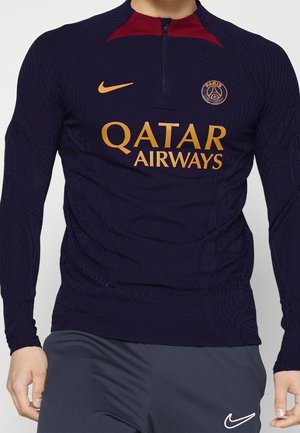 Granatowy długi rękaw koszulki piłkarskiej Paris Saint-Germain z bordowym kołnierzem oraz złotymi logo Qatar Airways, Nike i klubu.