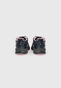 Chaussures de sport noires et roses avec une tige en maille texturée, une semelle rembourrée et un talon lisse, conçues pour le confort et le soutien.