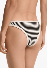 Bikini donji dio s crno-bijelim prugama i bež elastičnim pojasom. Tkanina izgleda teksturirano, s uskim i niskim krojem.