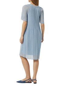 Blauwe jurk met patronen, korte mouwen, geplooid ontwerp en doorschijnende textuur. Gecombineerd met blauwe stoffen slingback ballerina's.