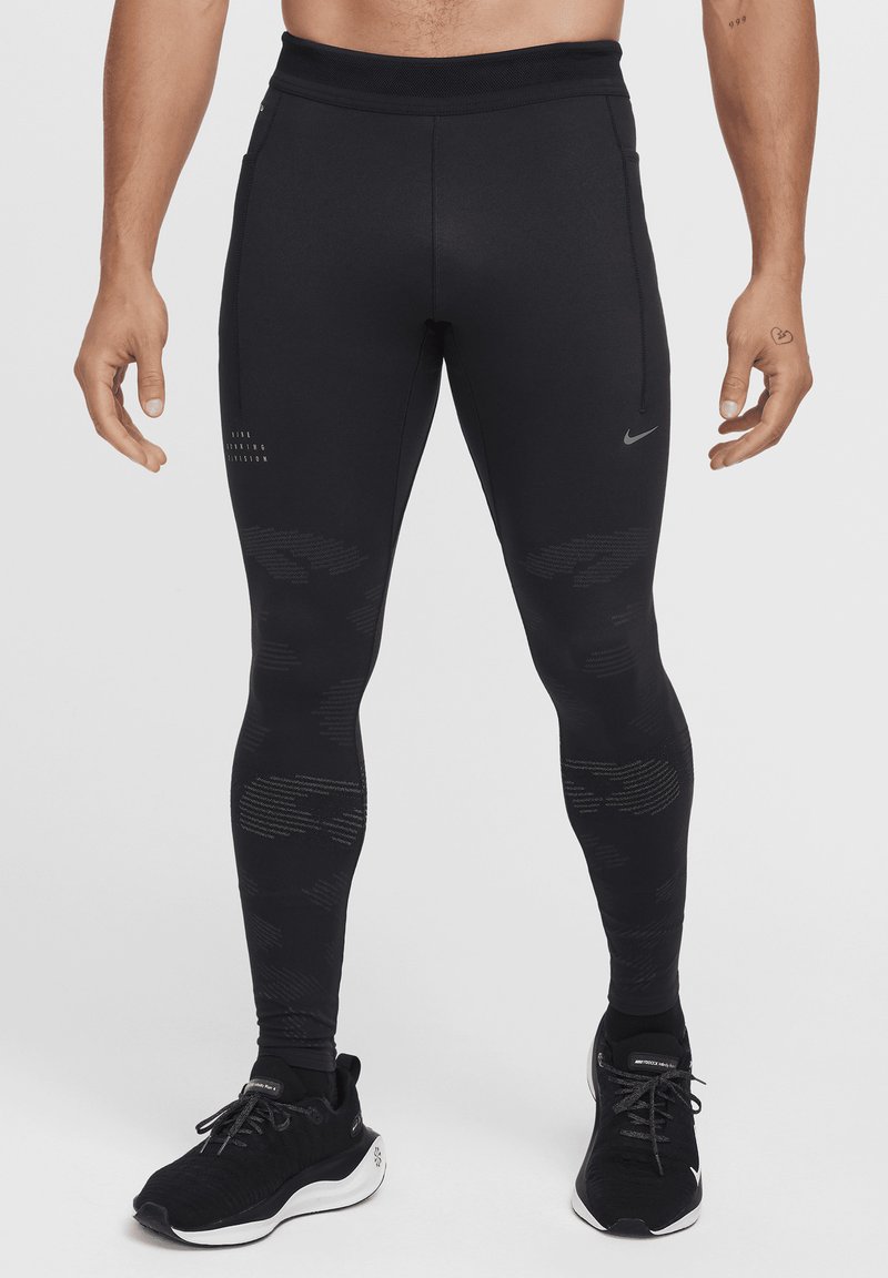 Leggings de sport noirs avec une texture lisse, un design ajusté, des accents réfléchissants et un motif subtil sur le bas des jambes. Comprend des poches latérales.