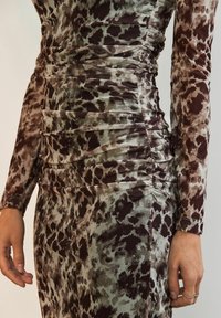 Rochie cu mânecă lungă, ajustată, dintr-un material texturat, cu un model de imprimeu animal în nuanțe de maro și verde. Dispune de drapaje pe părțile laterale.