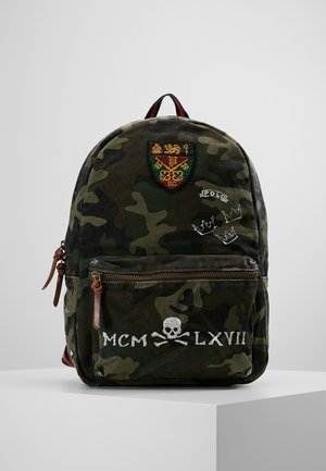 Plecak moro z przednią kieszenią, skórzanymi uchwytami zamka, wyszywanym herbem, napisem "POLO", trzema szkicami koron oraz czaszką z napisem "MCM LXVII" poniżej.