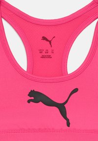 Roza športna modrčka z black Puma logotipom, designom racerback in gladkim, raztegljivim materialom s šivi. Oznaka vidna znotraj.