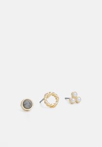 Ensemble de trois boucles d'oreilles : une avec une pierre grise, un design en or tordu, et un trio de petites perles, toutes avec des accents en métal.
