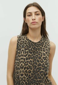 Top senza maniche con stampa leopardata, caratterizzato da un collo rotondo, un tessuto testurizzato e una cucitura frontale visibile, che combina tonalità di marrone e nero.