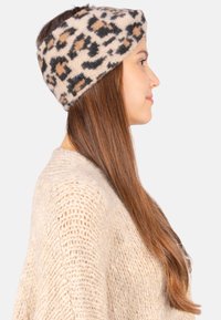 Bandeau à imprimé léopard en mélange de laine douce, avec une base beige clair et des taches noires et brunes, conçu pour couvrir les oreilles.