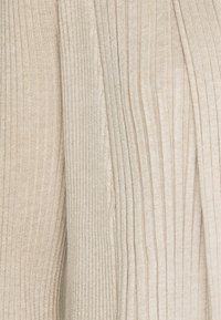 Tejido de color beige con relieve, que combina secciones lisas y texturizadas. Un ligero brillo aporta un aspecto suave, mientras que las rayas verticales realzan el diseño.