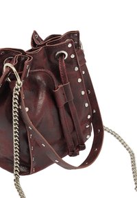 Burgundowa skórzana torba typu bucket z srebrnymi ćwiekami, sznurkiem do zawiązywania i łańcuszkowym paskiem. Gładka tekstura z lekko błyszczącym wykończeniem.