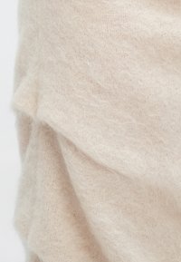 Světlé béžové pletené tkaní s měkkou, chlupatou texturou; obsahuje jemně splývavý design a tenký vzor tkaní.