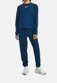 Ensemble sweat-shirt et pantalon bleu marine en tissu doux. Caractéristiques : col rond et logo sur la poitrine et la cuisse. Comprend des poignets élastiques.