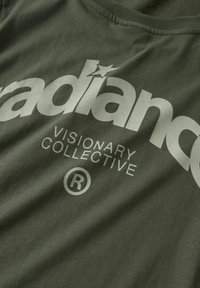Oliven grøn bomulds t-shirt med fremtrædende hvid tekst: "radiance VISIONARY COLLECTIVE" og et registreret varemærkesymbol.