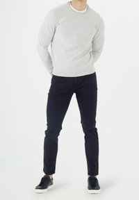 Pull à col rond gris clair, pantalon noir ajusté, et baskets noires à semelles blanches. Tissu lisse, coupe près du corps, sans motifs apparents.